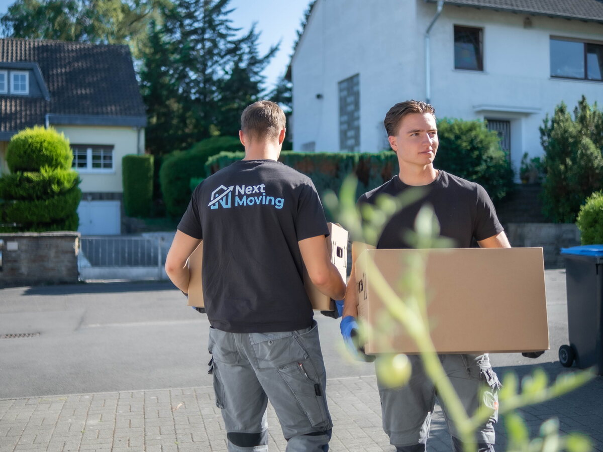 Jannes Wesselmann und ein Helfer tragen Umzugskartons